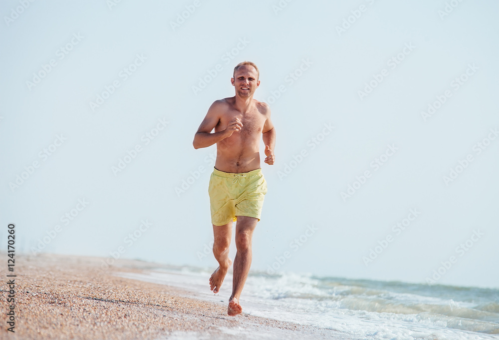 Man jogging on the sea surf line at morning time