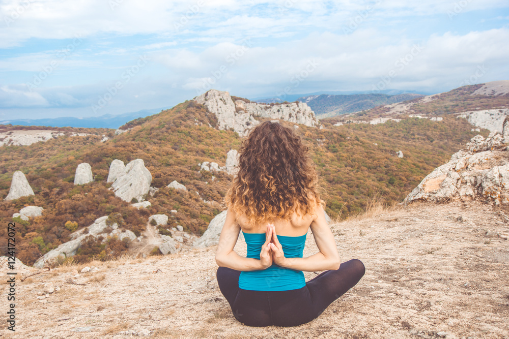 Girl doing yoga in mountains landscape