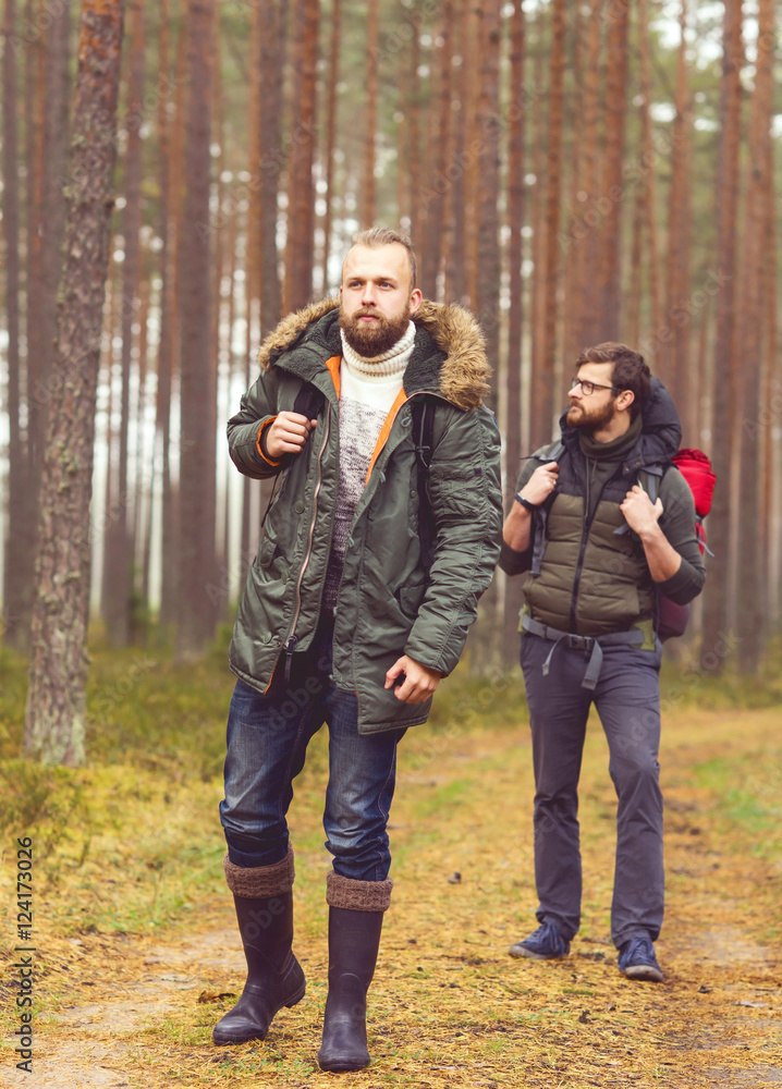 Men with backpacks and beards hiking in the forest