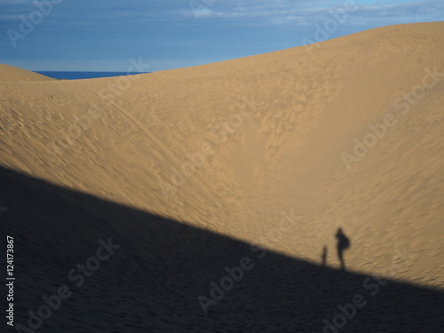 Shadows of child and adult hiking in dunes of Maspalomas