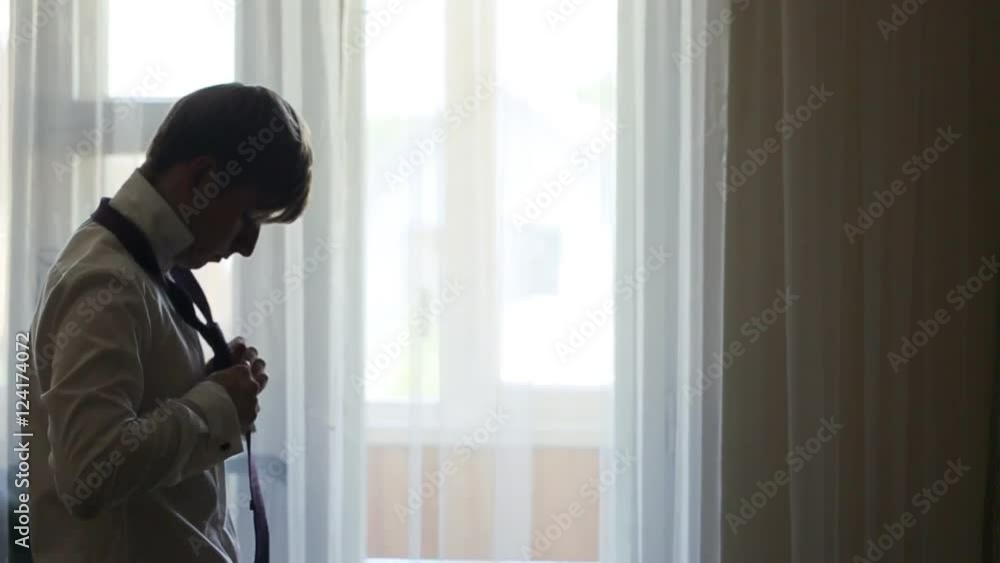 A picture of a groom fixing a fine tie carefully, neat white shirt on A picture of a groom fixing a fine tie carefully, neat white shirt on