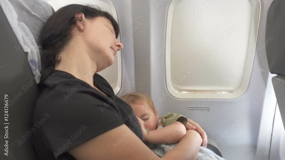 Mother with a baby sleeping in the aircraft cabin , sitting around ...