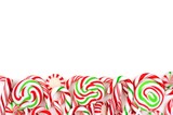 Christmas candy bottom border with lollipops, peppermints and candy canes over a white background