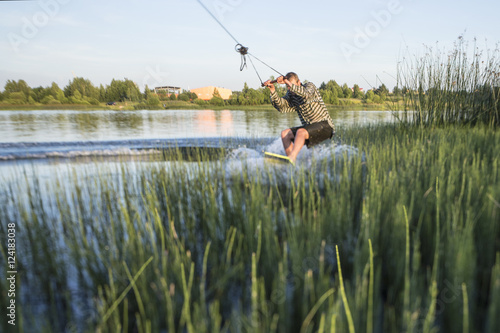 Wakeskater in a cable park going through plants