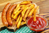 Homemade fast food, portion of french fries, ketchup, grilled sausages, on wooden board.