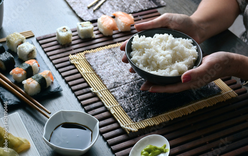 Woman preparing sushi rolls at home photo