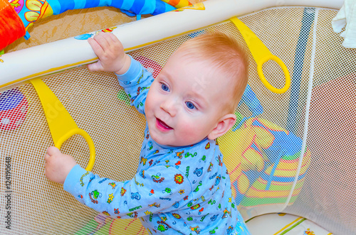 little boy standing in the playpen for babies