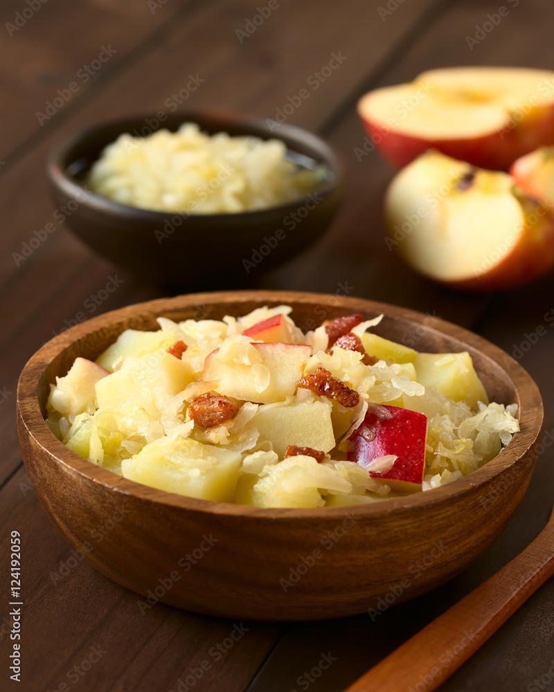 Potato, sauerkraut and apple salad with fried bacon served in wooden bowl, photographed with natural light (Selective Focus, Focus in the middle of the salad) Potato, sauerkraut and apple salad with fried bacon served in wooden bowl, photographed with natural light (Selective Focus, Focus in the middle of the salad)