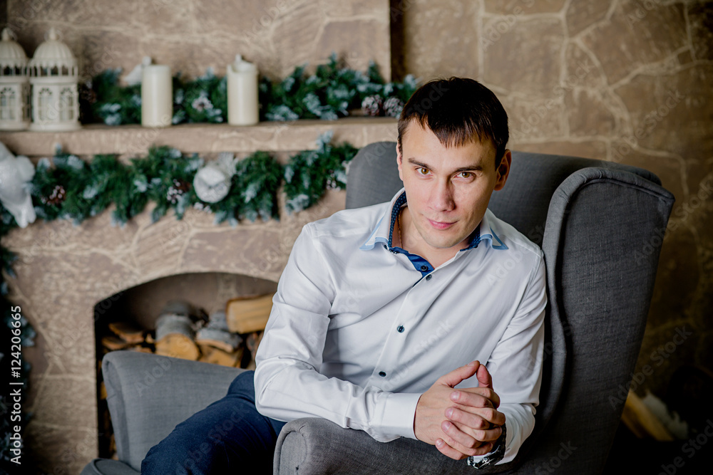 young man sitting on background of Christmas interior young man sitting on background of Christmas interior