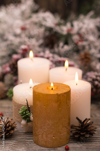 Fir branch in snow  lighted candle  cone on wooden background. Christmas theme