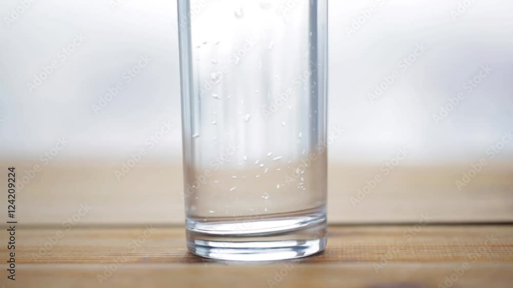 water pouring into glass on wooden table water pouring into glass on wooden table