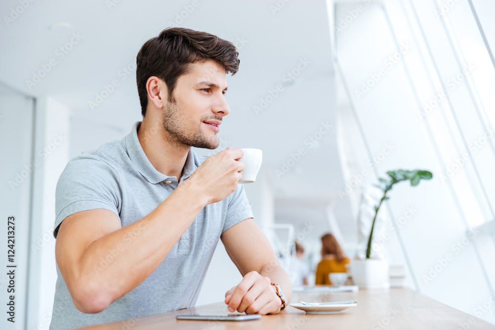 Smiling casual young man drinking coffee in cafe Smiling casual young man drinking coffee in cafe