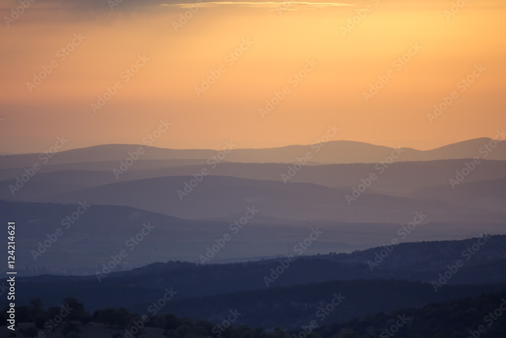 Orange and yellow sunset with mountains silhouettes. Gradient vivid nature background. Orange and yellow sunset with mountains silhouettes. Gradient vivid nature background.