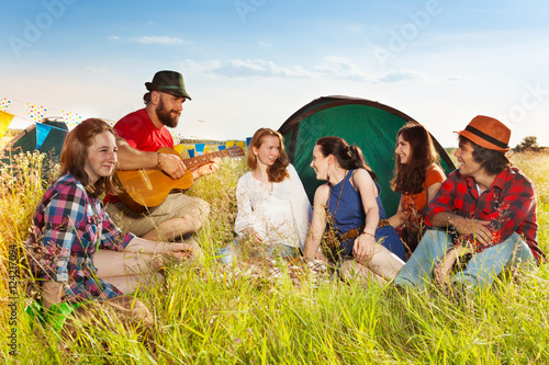 Young people singing to the guitar at campsite