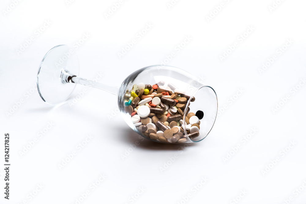 Medical capsules and tablets inside wine glass Medical capsules and tablets inside wine glass