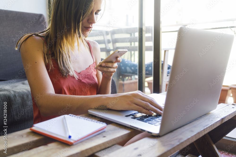 Young woman using mobile and laptop at home Young woman using mobile and laptop at home