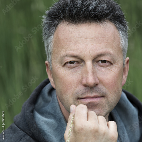 Canvas Print Portrait of handsome mid-adult man posing on summer meadow with