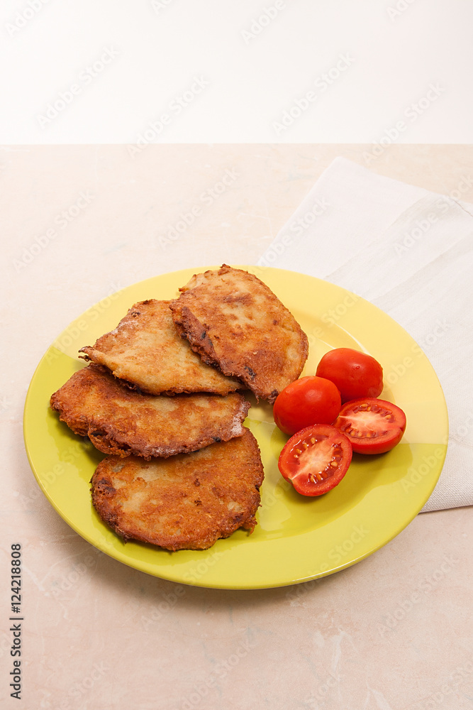 Potato pancakes with meat and tomatoes on green plate in Belarus