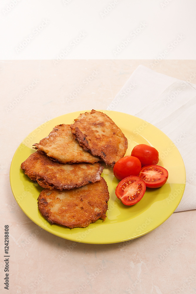 Potato pancakes with meat and tomatoes on green plate in Belarus Potato pancakes with meat and tomatoes on green plate in Belarus