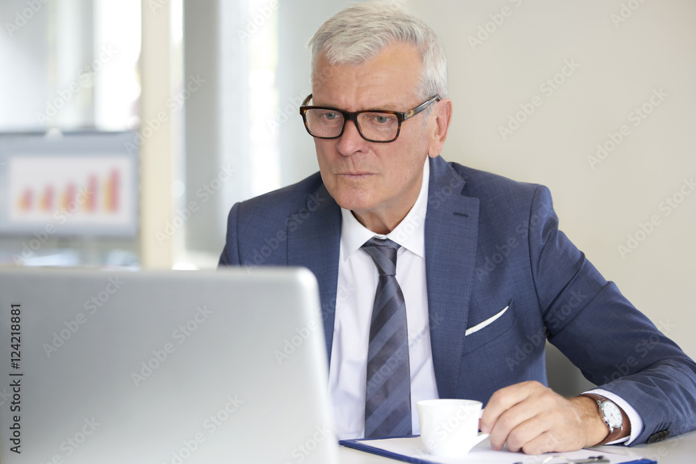 Financial businessman at work. Shot of a senior financial manager working at office in front of laptop and and doing some paperwork. Financial businessman at work. Shot of a senior financial manager working at office in front of laptop and and doing some paperwork.