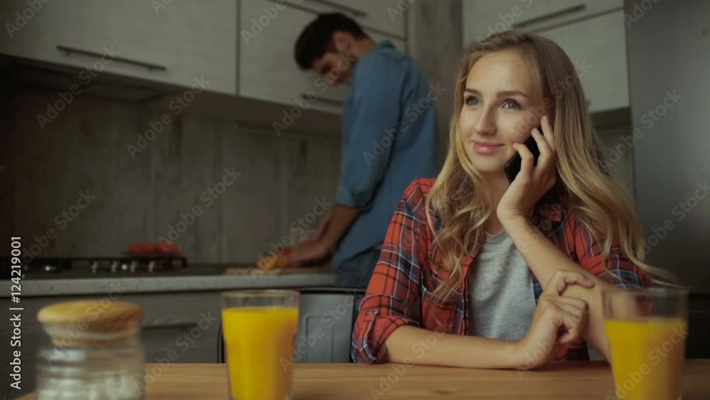 Woman talking on phone, while man preparing food. Woman talking on phone, while man preparing food.