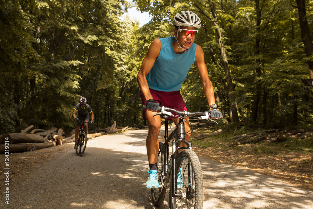 Fototapeta premium Two mountain bikers riding bike in the forest on dirt road.