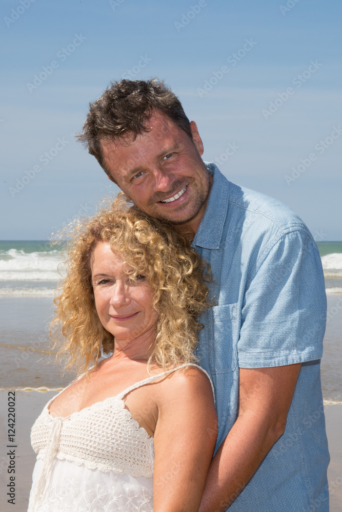 Cheerful mature couple embracing by the beach