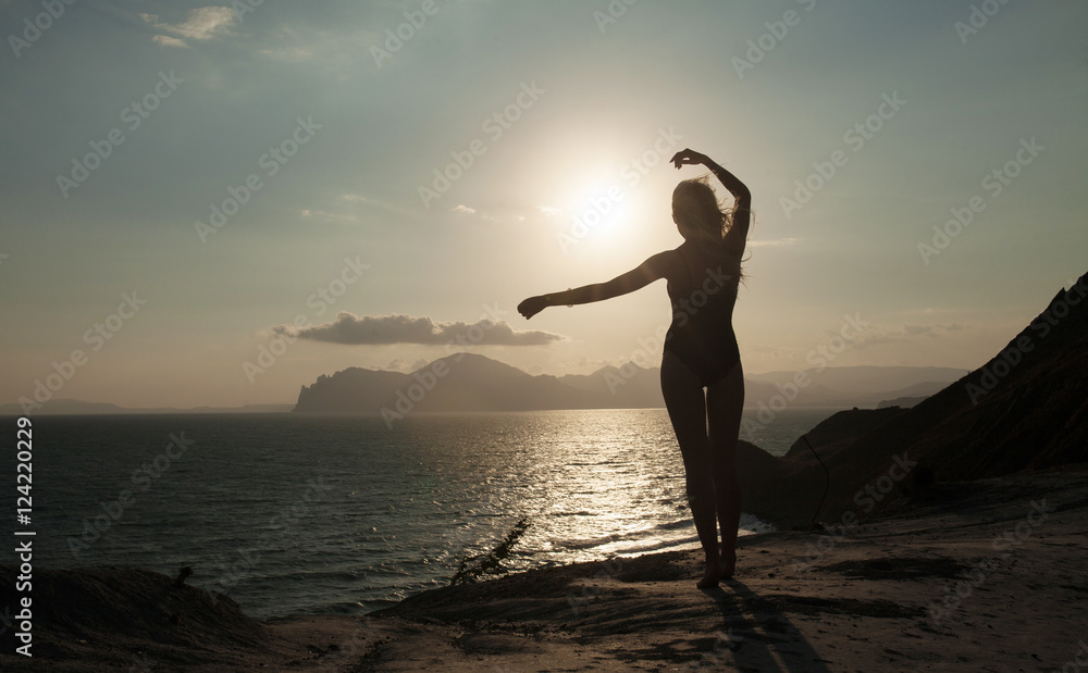Silhouette of the woman standing at the beach during beautiful sunset.