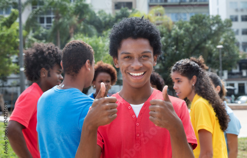 Young african american man with friends showing both thumbs