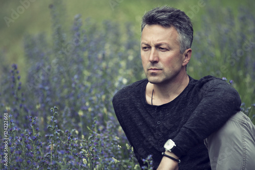 Portrait of handsome mid-adult man posing on summer meadow, imag photo