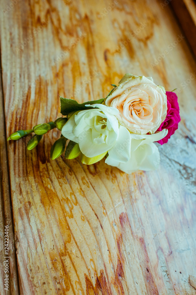 Boutonniere made of white and pink flowers lies on the windowsil Boutonniere made of white and pink flowers lies on the windowsil