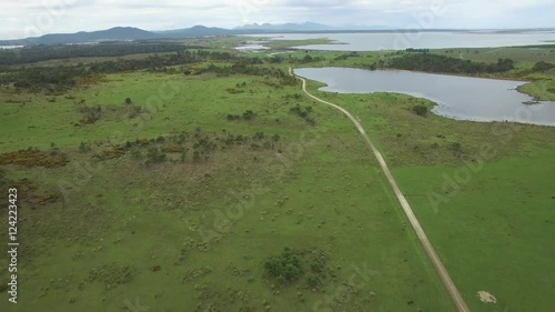 Forward flight over rural road and grasslands towards ocean in Tasmania, Australia photo