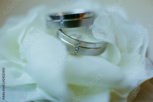 Wedding rings decorated with crystals lie on the delicate white