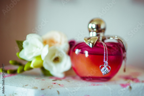 Round red parfume bottle stands on the table behind a white bout