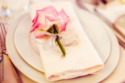 A bud of pink rose lies on the white plate