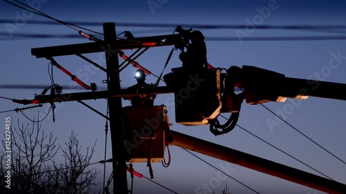 Silhouetted utility workers working on power line