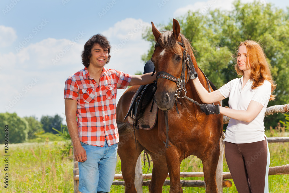 Obraz premium Happy young people walking with their bay horse