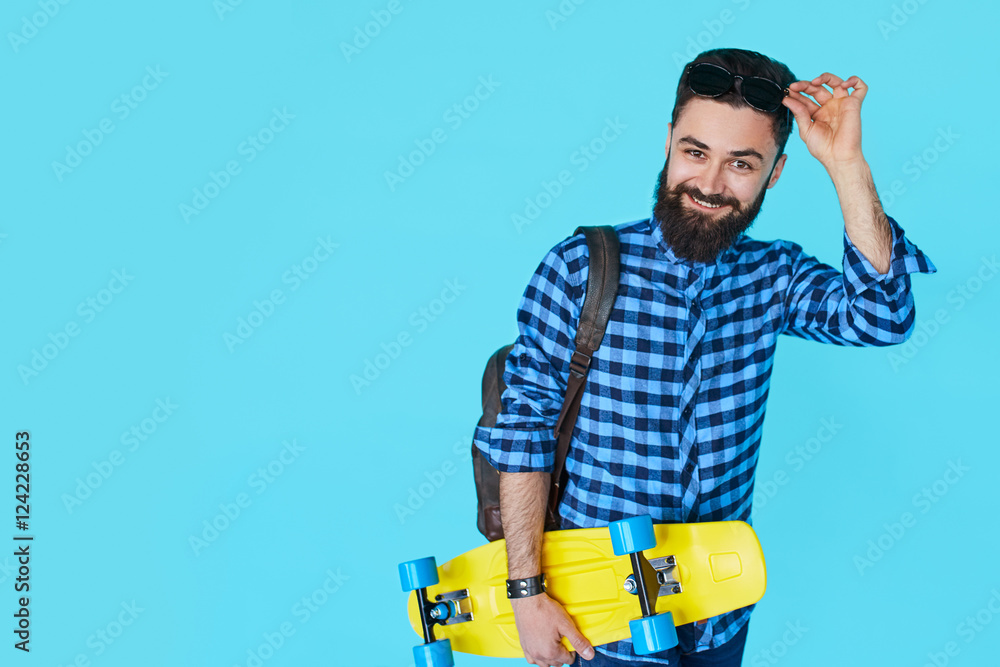 Hipster man over colorful blue background holding yellow skateboard Hipster man over colorful blue background holding yellow skateboard