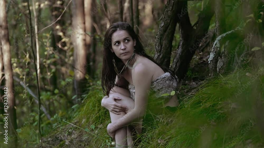 Attractive and a bit scared girl sitting on the hill and looking somewhere nervously Attractive and a bit scared girl sitting on the hill and looking somewhere nervously