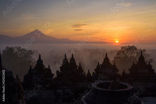 Die Stupas von Borobudur im Sonnenaufgang mit Vulkankegel im Hintergrund