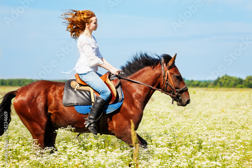 Young woman galloping horseback in flowery meadow © Sergey Novikov