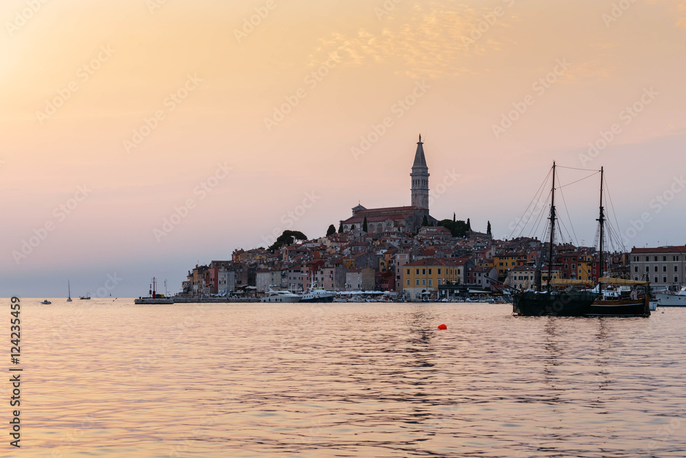 View of the historic part of Rovinj in Croatia during sunset. Above the town rises the Church of St. Euphemia. On the sea the ships.