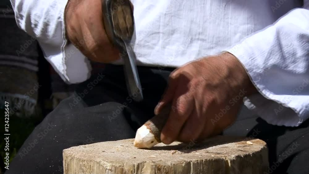 Village. Man Showing How to Use an ax to Make a Craft. Short Peg. Man Cutting Cortex Edge Around to Make it Even, Holding With Hand, Hitting. Closeup Village. Man Showing How to Use an ax to Make a Craft. Short Peg. Man Cutting Cortex Edge Around to Make it Even, Holding With Hand, Hitting. Closeup