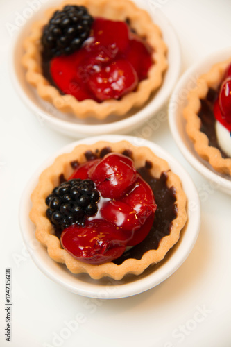  mini cherry pies/tarts on plates garnished with blackberry