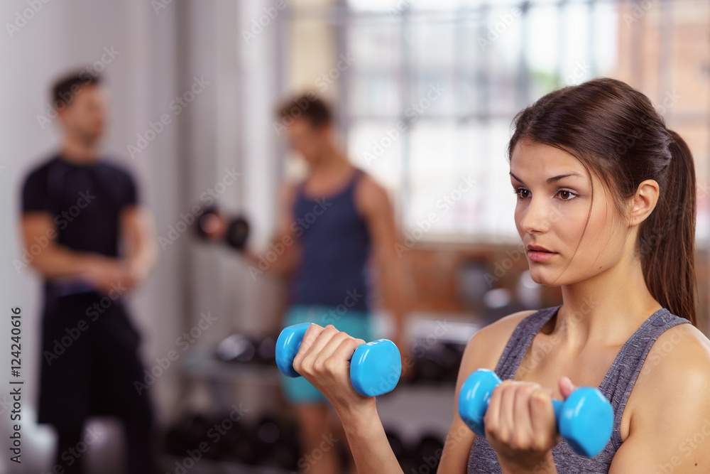frau trainiert mit gewichten im fitnessclub