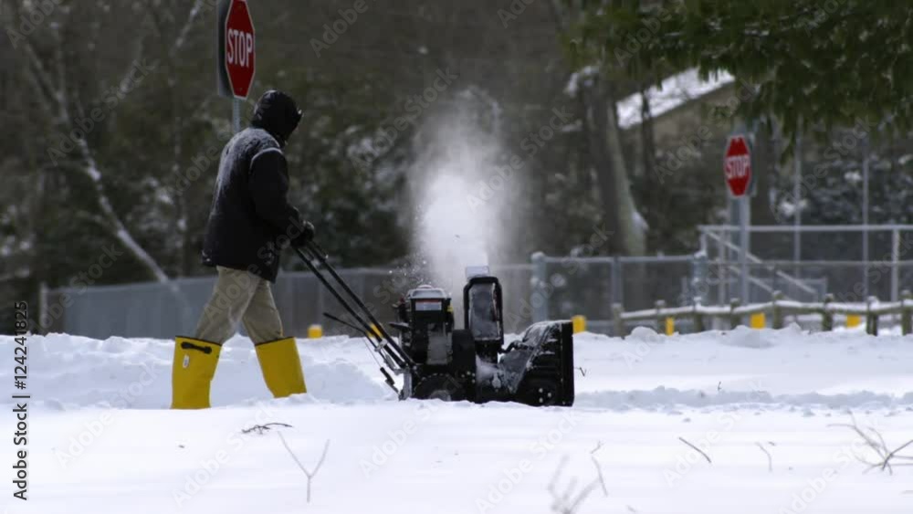 Slow motion of a man using snow blower in snow Stock Video Adobe Stock