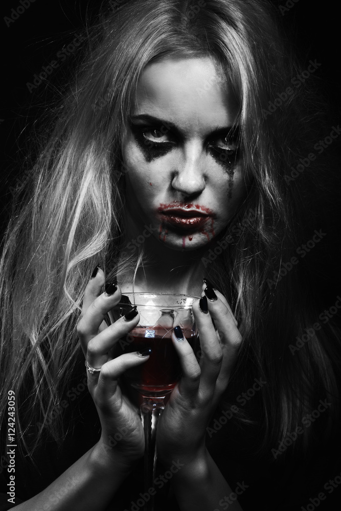 Fototapeta premium blond witch with bloody glass on black background, toned image