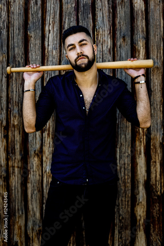 handsome young man in dark blue shirt with beat standing near wooden wall