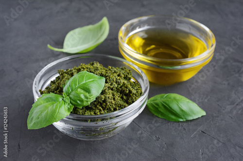 Pesto and olive oil in glass bowl and fresh basil leaves