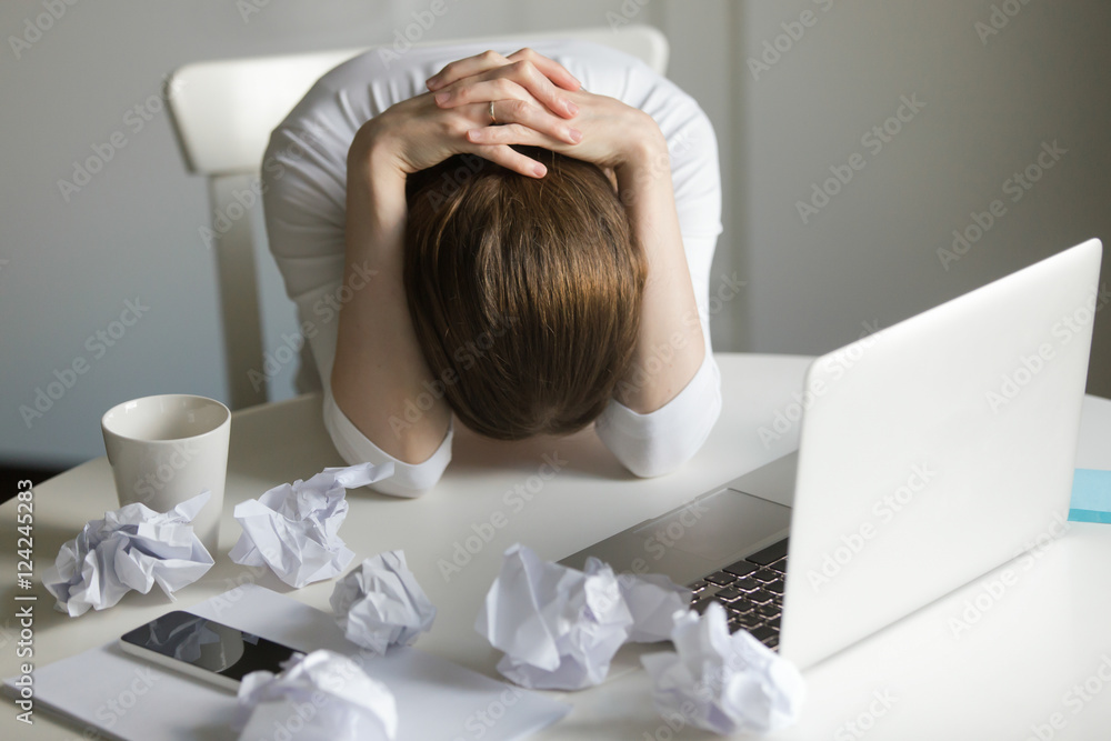 Φωτογραφία Portrait of a woman grabbing her head in despair at the desk near the laptop, her face down